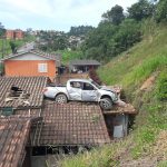 Motorista cai com caminhonete no telhado de residência em Orleans
